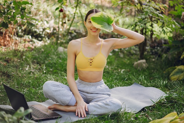 Foto grátis menina sentada em um parque de verão e segurando um laptop nas mãos