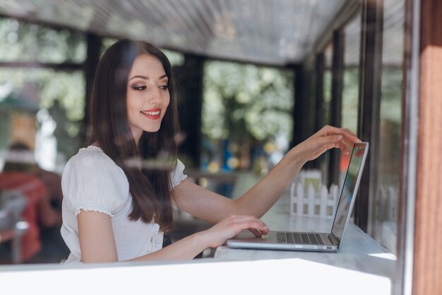 Menina sentada em um restaurante olhando para um laptop