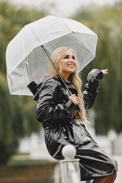 Menina sentada. Mulher com um casaco preto. Loira com um guarda-chuva.