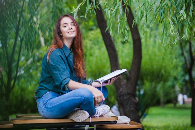 Foto grátis menina sentada na mesa fora, sorrindo