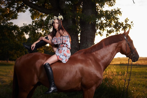 Menina sentada no cavalo marrom.