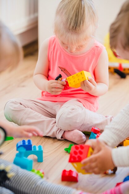 Menina sentada no chão brincando com brinquedos