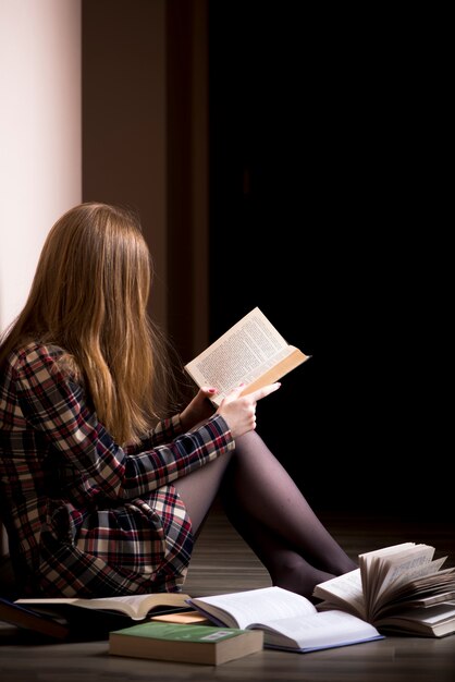 Menina sentada no chão, cercada de livros