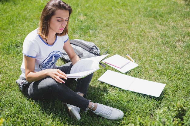 Menina sentada no parque segurando leitura de caderno