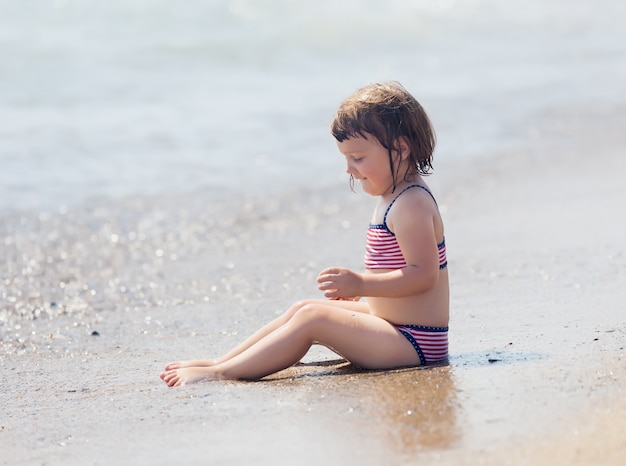 menina siting na praia de areia