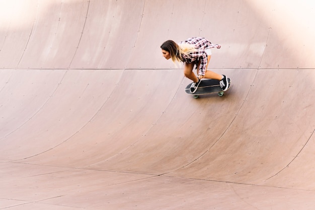 Menina skater desportiva em meio tubo