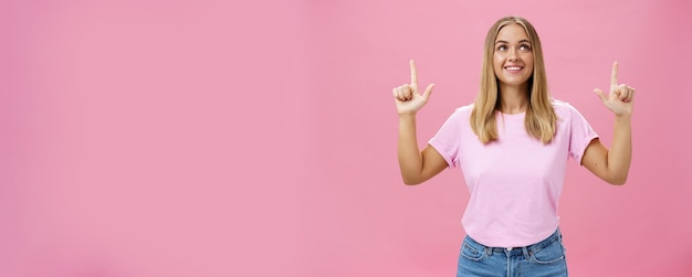 Foto grátis menina sonhando acordada apontando e olhando com expressão otimista e admirada sorrindo alegremente enjo