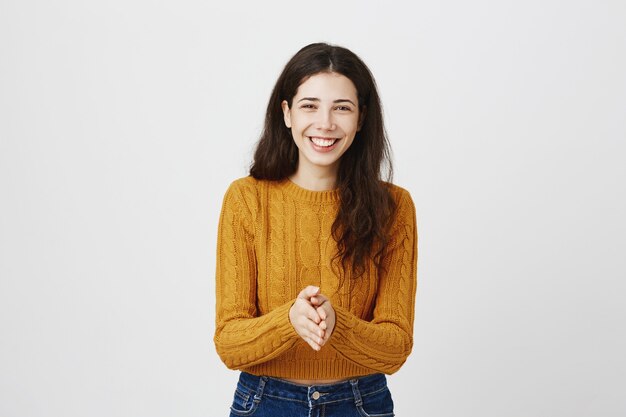 Menina sorridente agradecida juntando as mãos e parecendo feliz