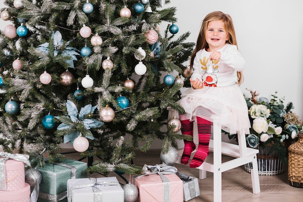 Menina sorridente ao lado da árvore de Natal