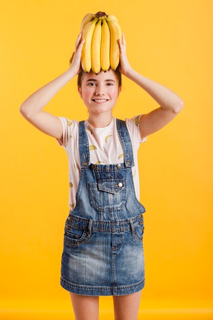 Menina sorridente com bananas