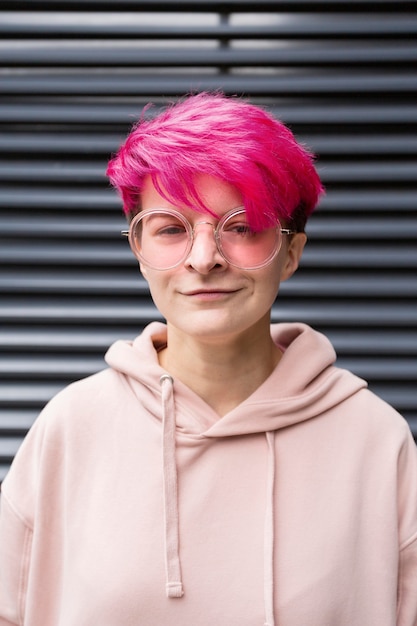 Menina sorridente com cabelo rosa e óculos