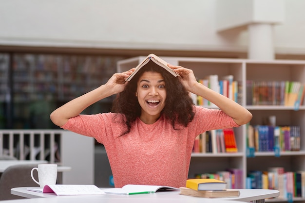 Menina sorridente com livro na cabeça