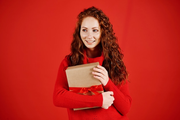 Menina sorridente com presente de natal olhando para o espaço da cópia