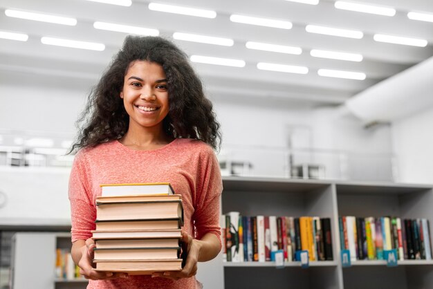 Menina sorridente de baixo ângulo com pilha de livros