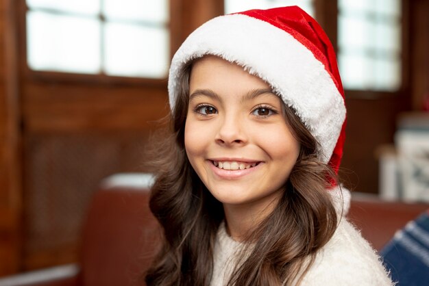 Menina sorridente de close-up com chapéu de Natal
