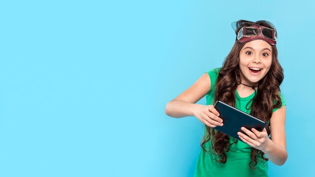 Foto grátis menina sorridente de cópia-espaço jogando no tablet