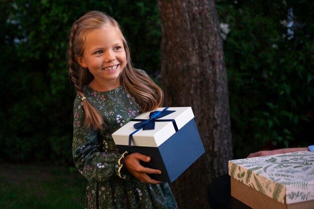 Menina sorridente de tiro médio segurando presente