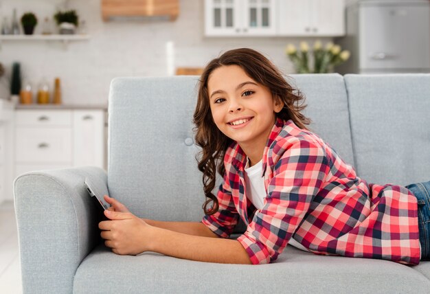 Menina sorridente de vista lateral com tablet em casa