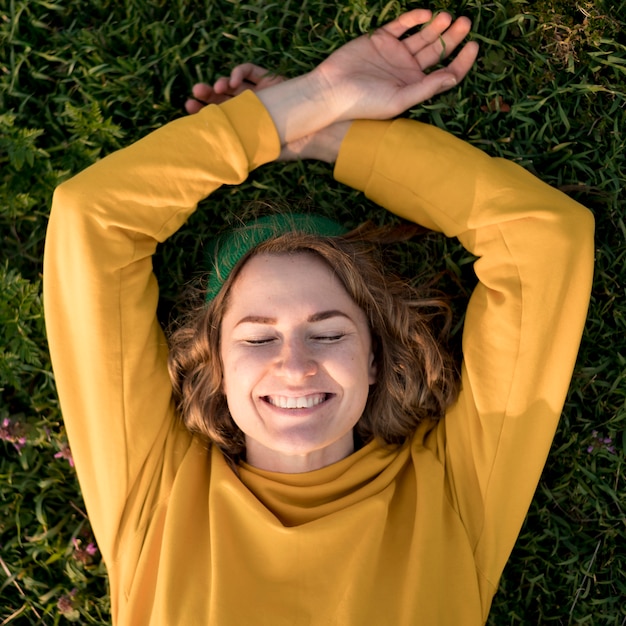 Menina sorridente de vista superior, ficar na grama