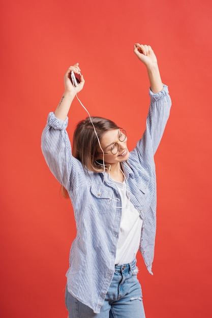 Foto grátis menina sorridente em roupas casuais e fones de ouvido dançando mãos em movimento.