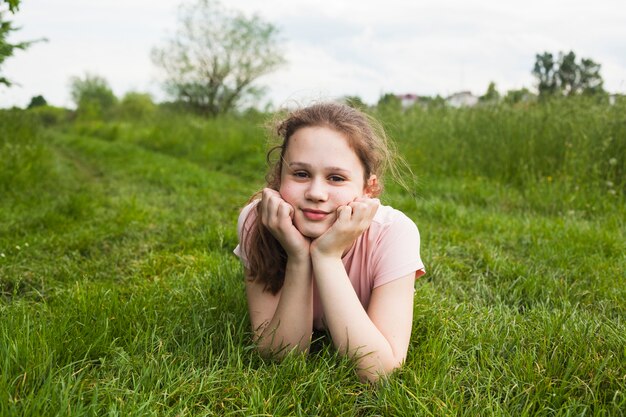 Menina sorridente, mentir grama, e, olhando câmera, parque