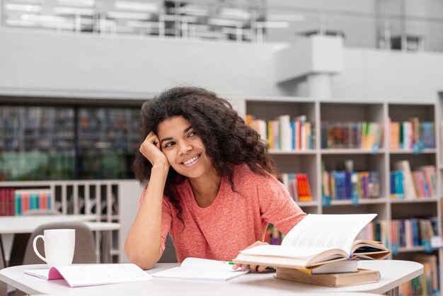 Menina sorridente na biblioteca estudando