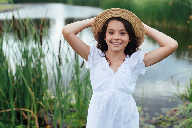 Menina sorridente posando à beira do lago