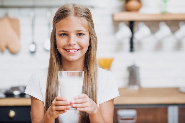 Menina sorridente, segurando um copo de leite