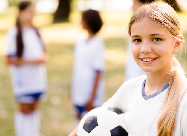 Menina sorridente segurando uma bola de futebol