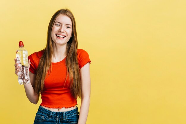 Menina sorridente segurando uma garrafa com espaço de cópia