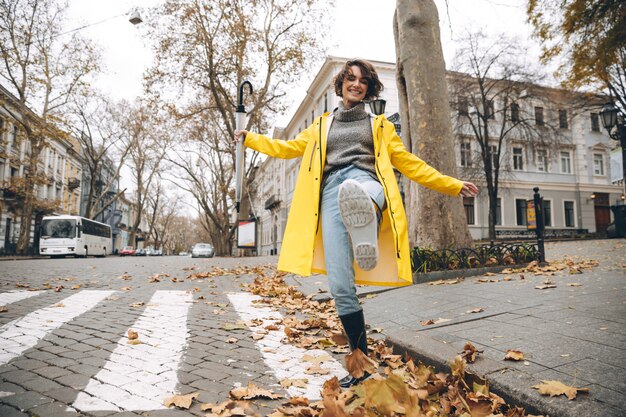 Menina sorridente, vestida com capa de chuva e botas de borracha