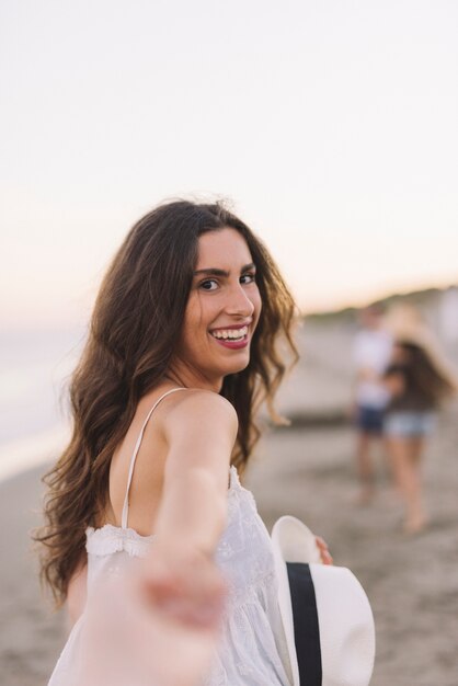 Menina sorrindo puxando a mão na praia