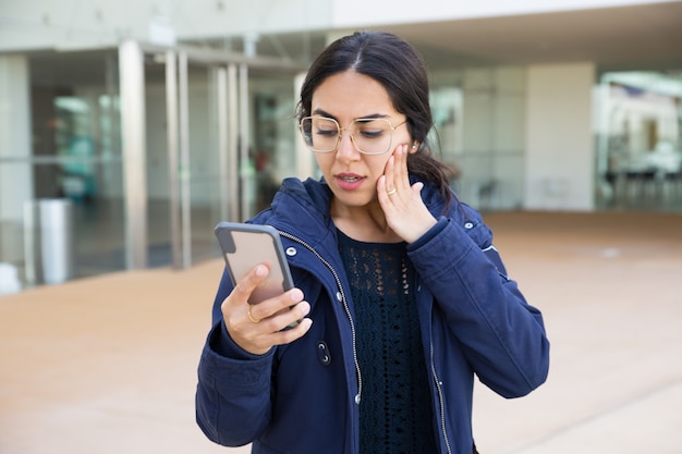 Menina surpreendida lendo na tela do smartphone