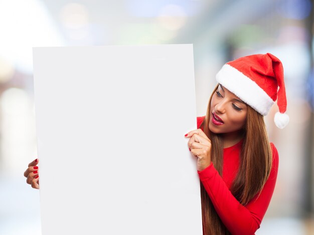 menina surpreendida que prende um poster vazio com fundo borrado