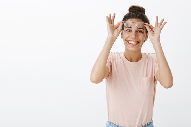 Menina surpresa e animada com óculos posando contra a parede branca