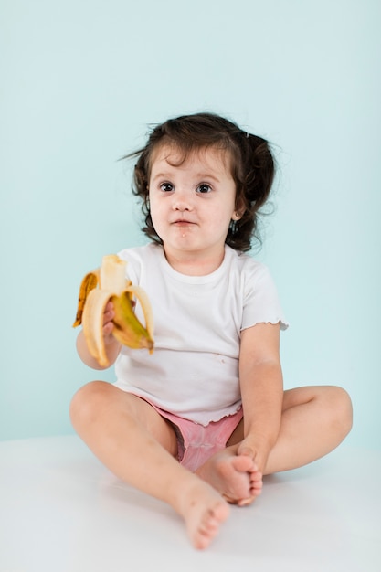 Menina tímida, segurando uma banana