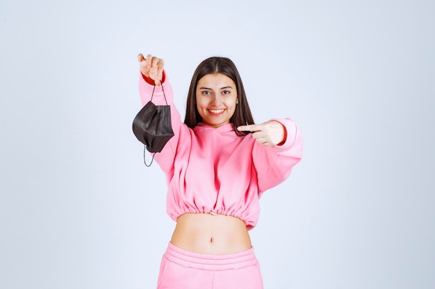 Foto grátis menina tirando a máscara preta e apontando para ela.