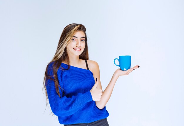 Menina tomando uma xícara de café e apreciando o sabor.