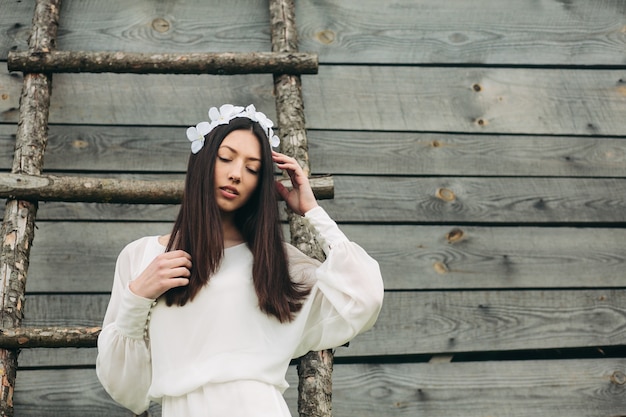 Menina triguenha no vestido branco e grinalda floral