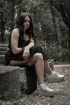 Menina triste de vestido preto sentada sozinha no banco