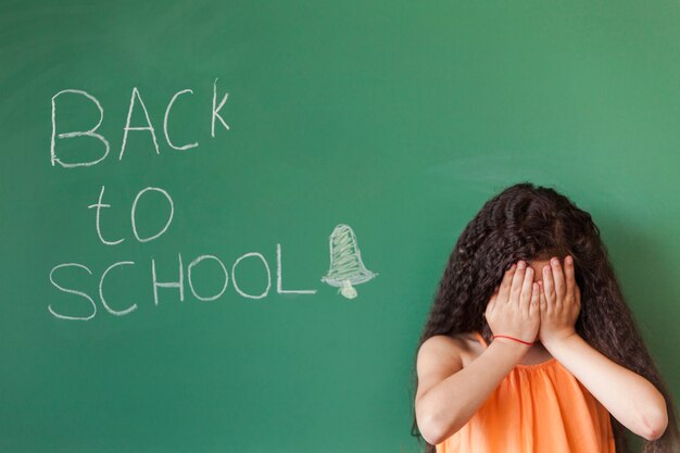 Menina triste no quadro negro na sala de aula