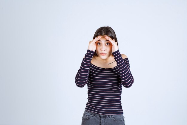 Menina unindo as mãos na testa e olhando para a frente.