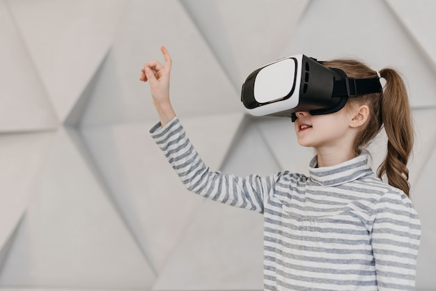Menina usando fone de ouvido de realidade virtual e segurando a mão no ar