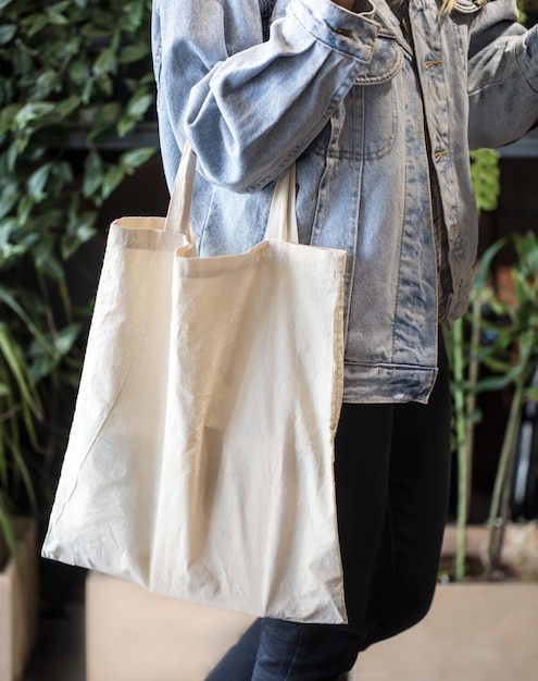 Menina vestida com uma jaqueta jeans segurando uma bolsa ecológica