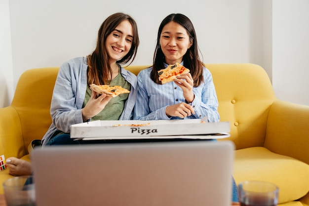 Foto grátis meninas alegres comendo pizza e assistindo comédia