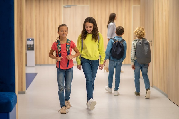 Meninas andando e meninos atrás de costas para a câmera