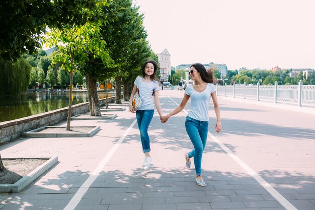 Meninas andando no pavimento de mãos dadas