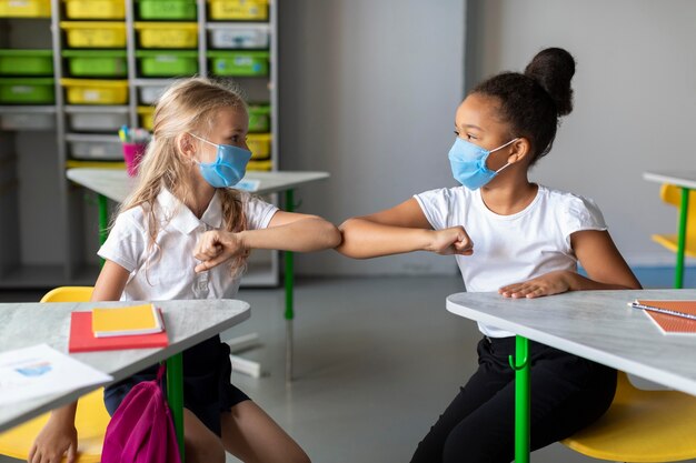 Meninas batendo o cotovelo na sala de aula