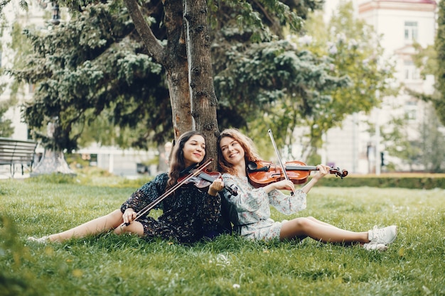 Meninas bonitas e românticas em um parque com um violino