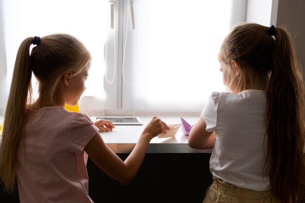 Meninas brincando com papel de origami em casa